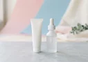 Tretinoin vs retinol skincare containers: a plain white tube beside a frosted dropper bottle on a pale grey surface